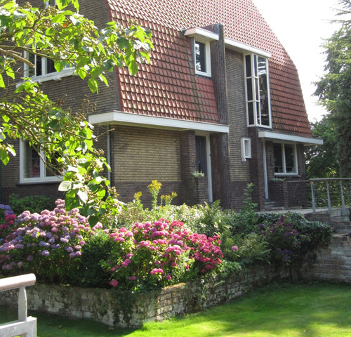 Villa Cuijk::Frissere uitstraling voor het houtwerk van bruin naar wit.::Houtwerk afwassen, slechte delen afbranden, langs het glas kitvoeg herstellen, plamuren, kitten, gronden, voorlakken en aflakken.